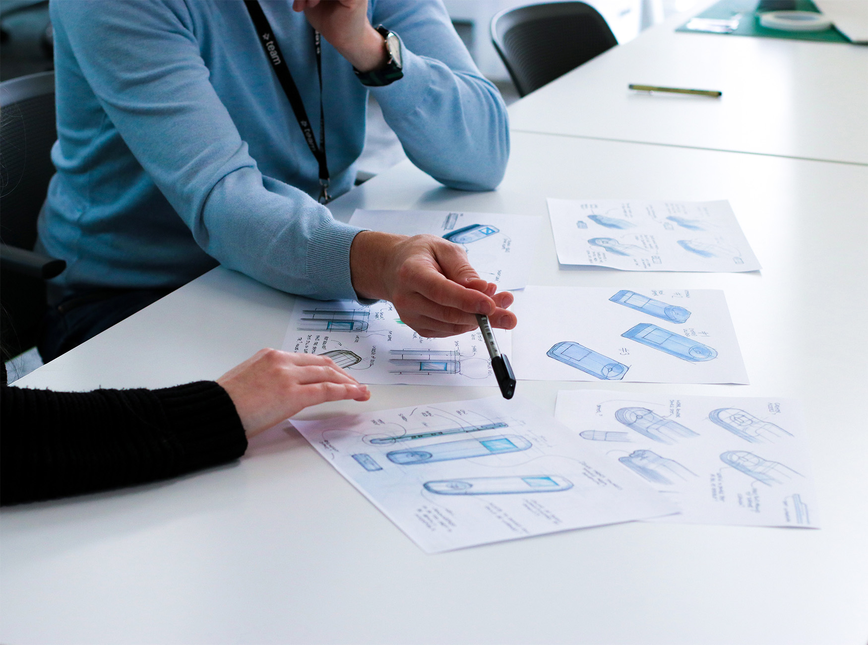 People sat at table pointing at device drawings